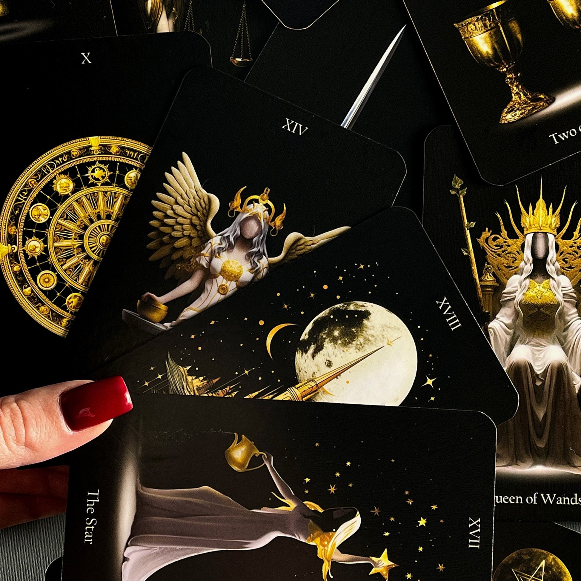 May include: Tarot cards with gold and black designs. The cards feature illustrations of angels, stars, and a moon. The cards are numbered XIV, XVII, and XVIII. The text on the cards reads 'The Star', 'Queen of Wands', and 'The Moon'.