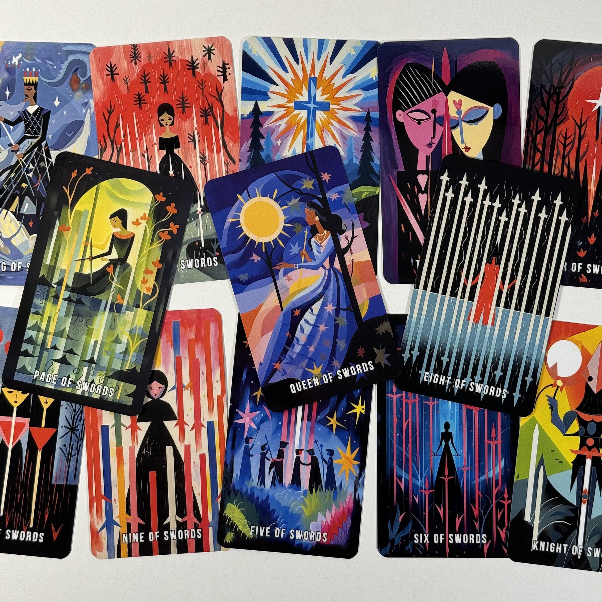 May include: A collection of tarot cards featuring colorful illustrations. The cards display various scenes with figures, celestial bodies, and geometric designs. The cards include text such as "Page of Swords," "Queen of Swords," and "Eight of Swords."